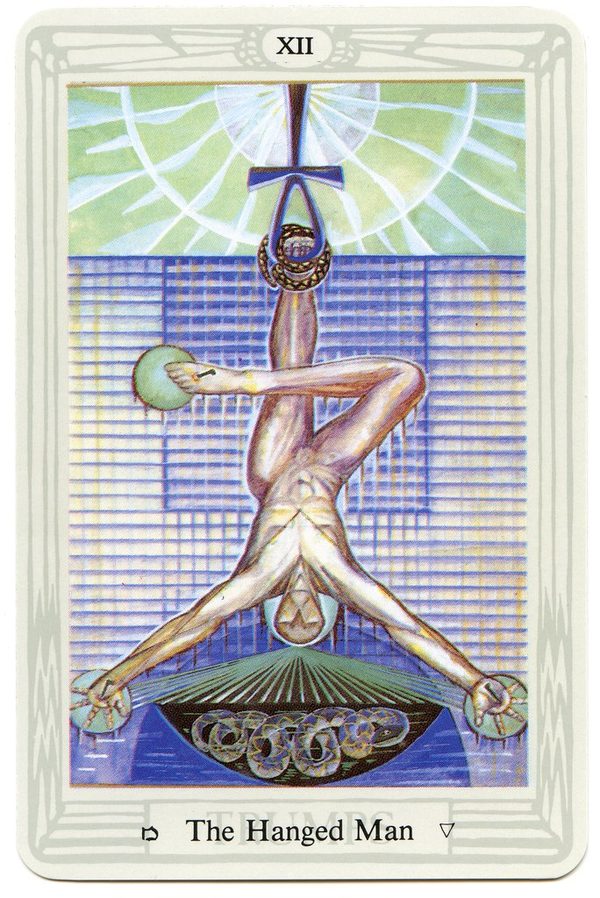 The Hanged Man, Thoth Tarot. A figure hangs upside-down by one foot from an ankh, his legs crossed and his arms held out to form a cross above a triangle. Nails pierce his hands and foot; a serpent rises beneath his head; the whole is drawn on a grid, the fixed matrix of the old Aeon.